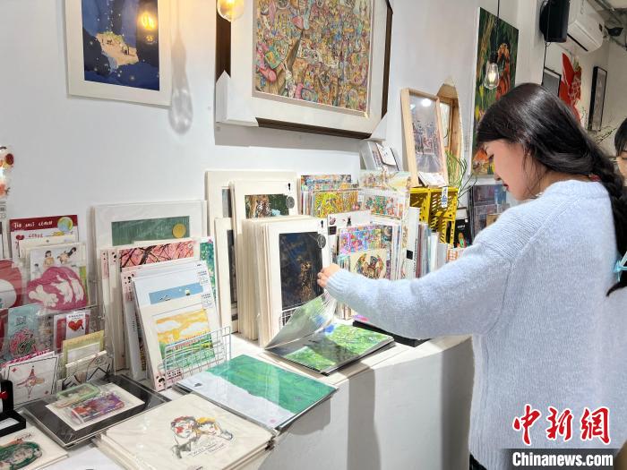 圖為藝術(shù)品商店內(nèi)，顧客挑選插畫作品?！＄婌?攝