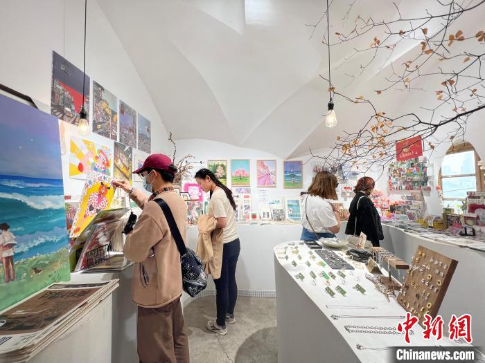 圖為藝術(shù)品商店內(nèi)，顧客挑選插畫作品?！＄婌?攝