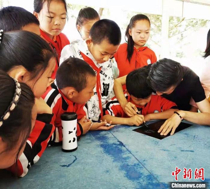 圖為朱增平(右一)教學(xué)生創(chuàng)作鍥金畫。(資料圖) 受訪者供圖