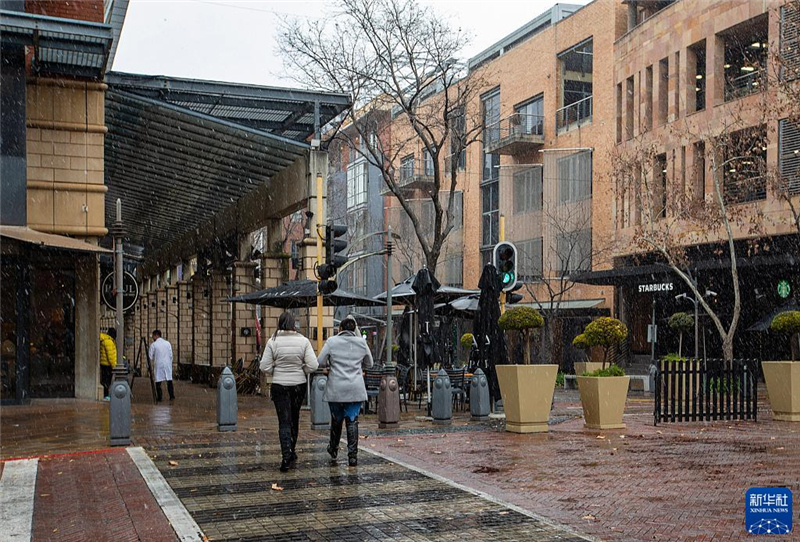 7月10日，在南非約翰內(nèi)斯堡一處商業(yè)區(qū)，人們?cè)谘┲行凶?。新華社記者 張譽(yù)東 攝