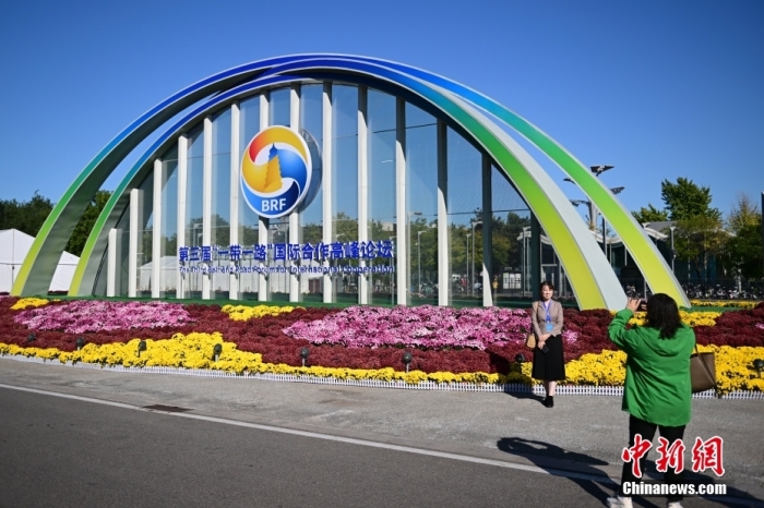 10月15日，北京，工作人員在國家會議中心外的第三屆“一帶一路”國際合作高峰論壇景觀布置前拍照留念。當日，位于國家會議中心的第三屆“一帶一路”國際合作高峰論壇新聞中心啟動試運行。據(jù)悉，第三屆“一帶一路”國際合作高峰論壇將于10月17日至18日在北京舉行。<a target='_blank' href='/'><p  align=