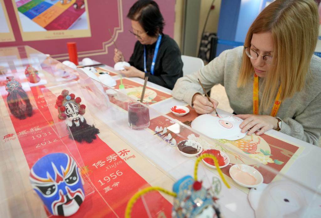 10月16日，在第三屆“一帶一路”國際合作高峰論壇新聞中心，來自比利時的記者（右）體驗畫京劇臉譜。新華社記者 王毓國 攝