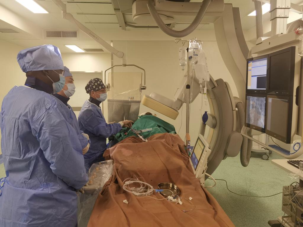 中國第29批援幾內亞醫(yī)療隊隊員、首都醫(yī)科大學附屬北京天壇醫(yī)院心內科副主任醫(yī)師王汝朋（右一）正在給患者做手術。（北京天壇醫(yī)院供圖）