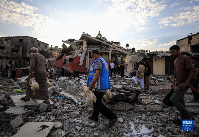 10月27日，在加沙地帶南部城市汗尤尼斯，人們經(jīng)過(guò)以軍襲擊后的房屋廢墟。