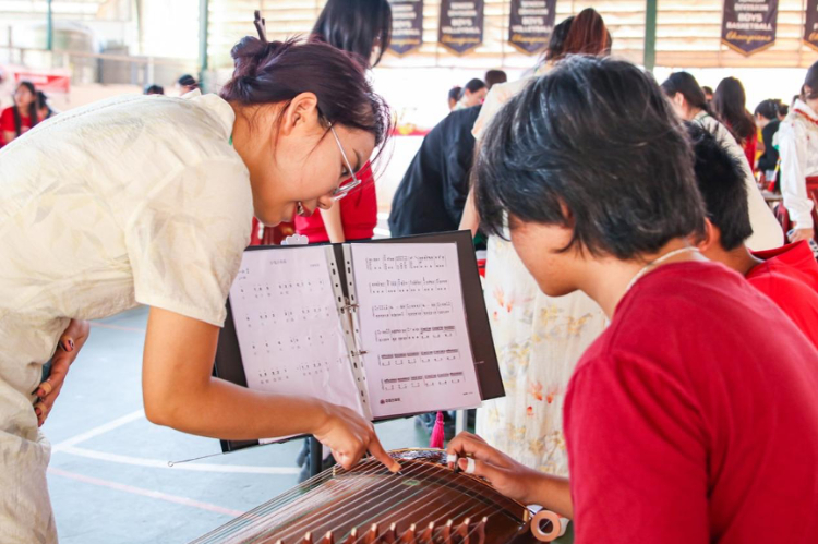 志愿者教師指導(dǎo)學(xué)生彈奏古箏。活動主辦方供圖