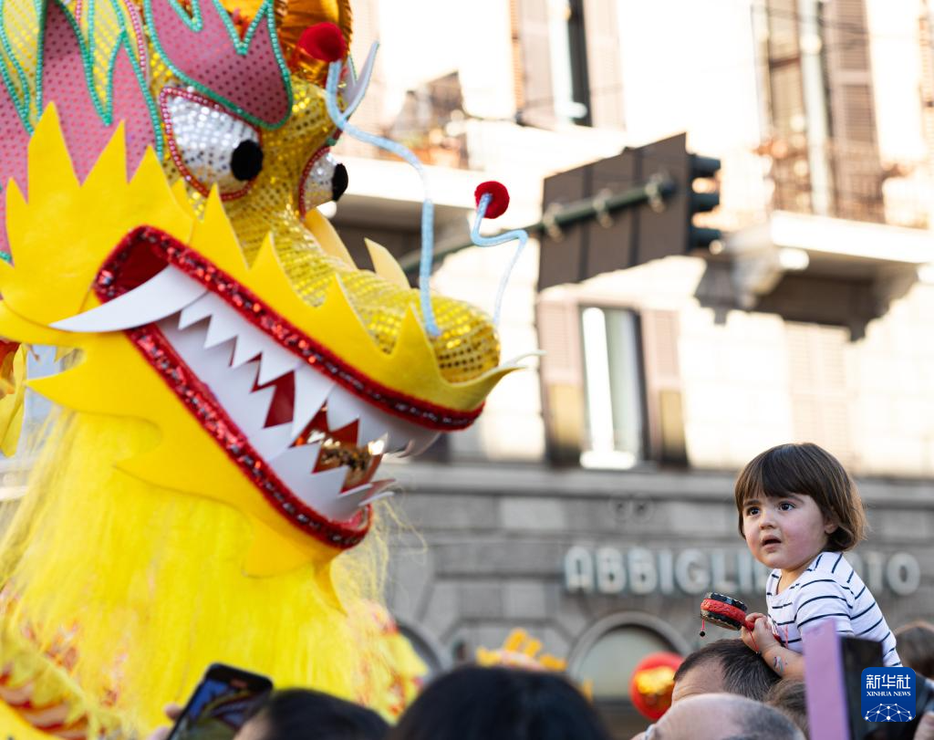 2月18日，在意大利羅馬，一名小朋友在彩妝巡游上觀看舞龍。新華社記者 李京 攝