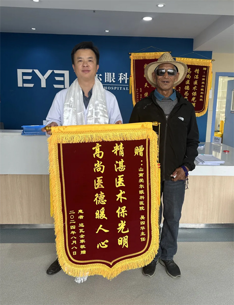 達(dá)瓦老人向吳四華（左）贈(zèng)送錦旗。受訪者供圖