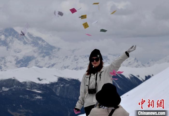 圖為5月14日，游客在西藏林芝色季拉山觀景臺(tái)拋灑“隆達(dá)”(風(fēng)馬旗，藏族民眾的一種祈福方式)。　李林 攝