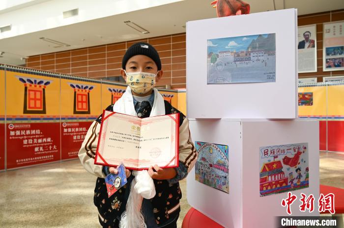 圖為一名獲獎學(xué)生與自己的繪畫作品合影。　趙朗 攝
