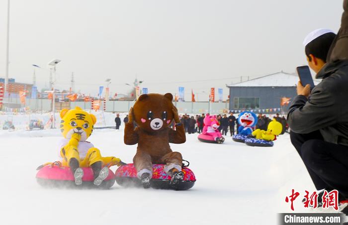 圖為臨夏市南龍鎮(zhèn)馬家莊村舉辦的鄉(xiāng)村文化旅游節(jié)上，游客穿著卡通服裝在體驗雪上飛碟項目。近年來，臨夏州形成了“春賞花、夏避暑、秋摘果、冬玩雪”的全季節(jié)旅游產(chǎn)品體系。(資料圖) 高展 攝