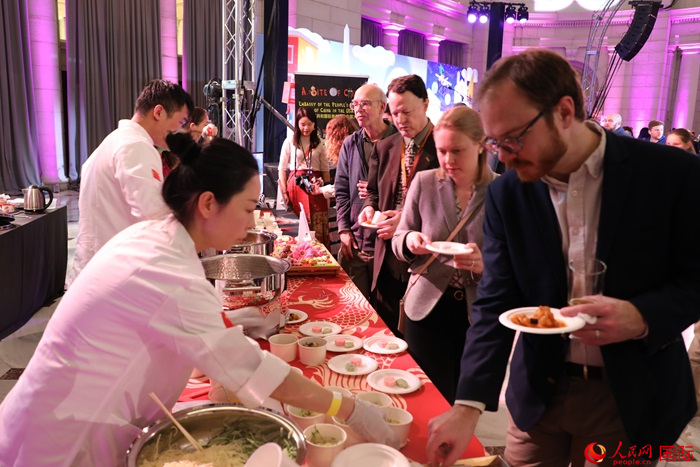 當(dāng)?shù)貢r(shí)間3月7日晚，華盛頓聯(lián)合車站廣場(chǎng)舉行駐美使團(tuán)“使館主廚挑戰(zhàn)賽”。圖為當(dāng)?shù)孛癖娫谥袊?guó)展臺(tái)前體驗(yàn)中國(guó)美食。人民網(wǎng)記者 李志偉攝