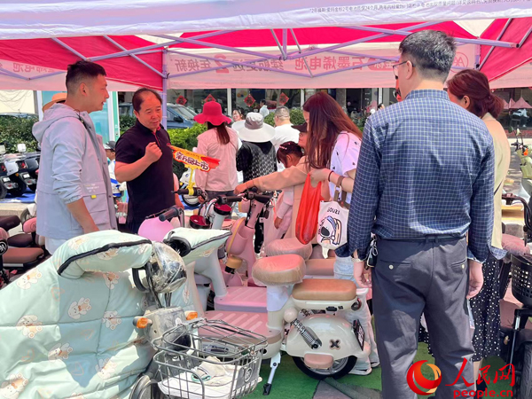某電動自行車品牌工作人員向消費者介紹以舊換新相關情況。人民網記者 杜燕飛攝