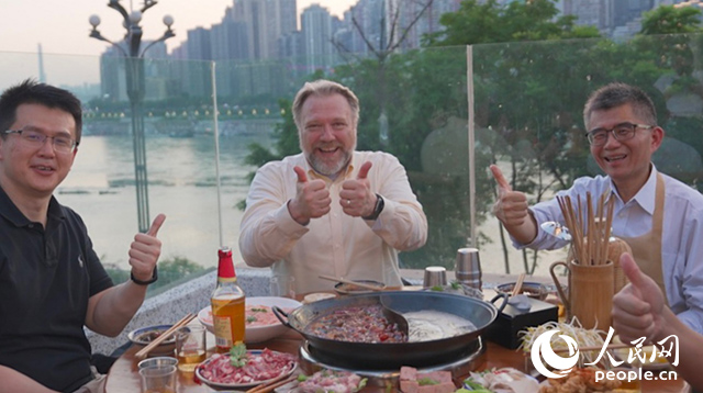 康寧顯示科技事業(yè)部全球拓建項(xiàng)目總監(jiān)軻寶華（中）和同事在重慶南濱路吃火鍋。人民網(wǎng)記者 蘇纓翔攝
