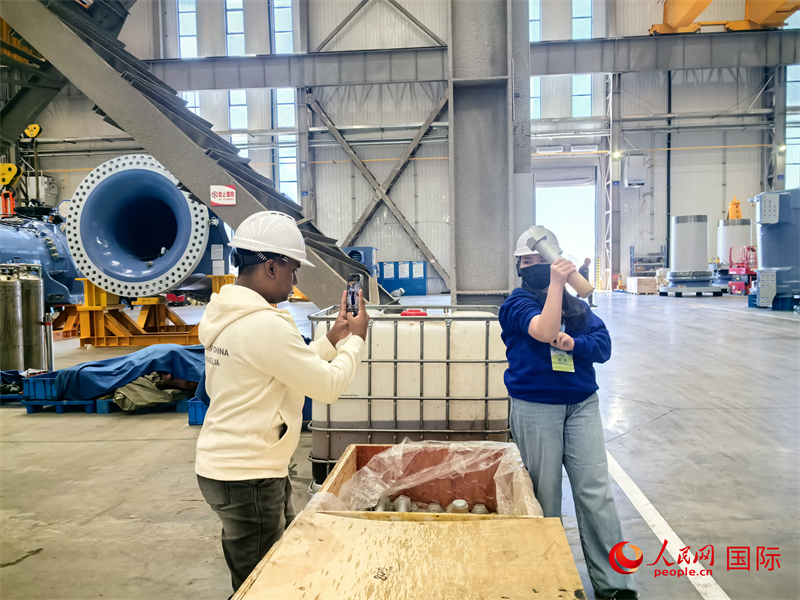 外媒記者掂量廠房內(nèi)的巨型螺栓。人民網(wǎng) 楊春燕攝