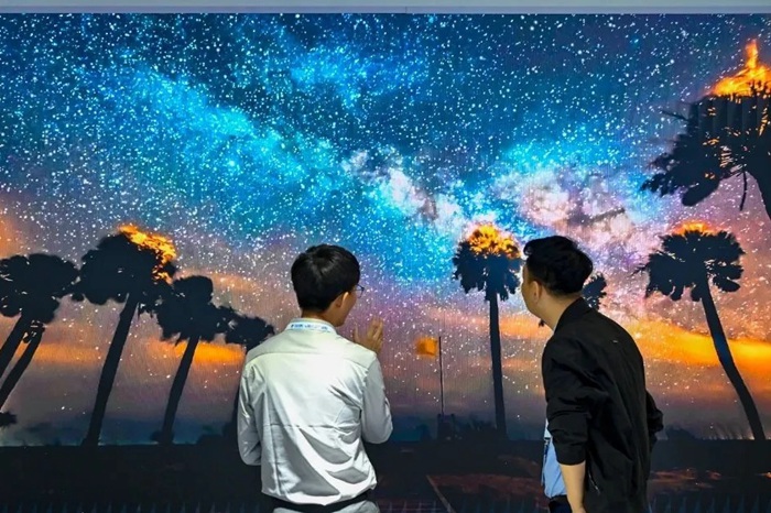 長春光博會希達電子展區(qū)，一位工作人員正在給一位觀眾講解。（長春新區(qū)供圖）