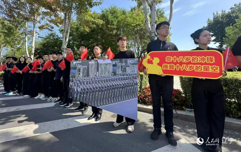 沈陽市人民廣場上，大學(xué)生們手持閱兵的圖片，告慰英烈。人民網(wǎng)記者 周頌雪攝