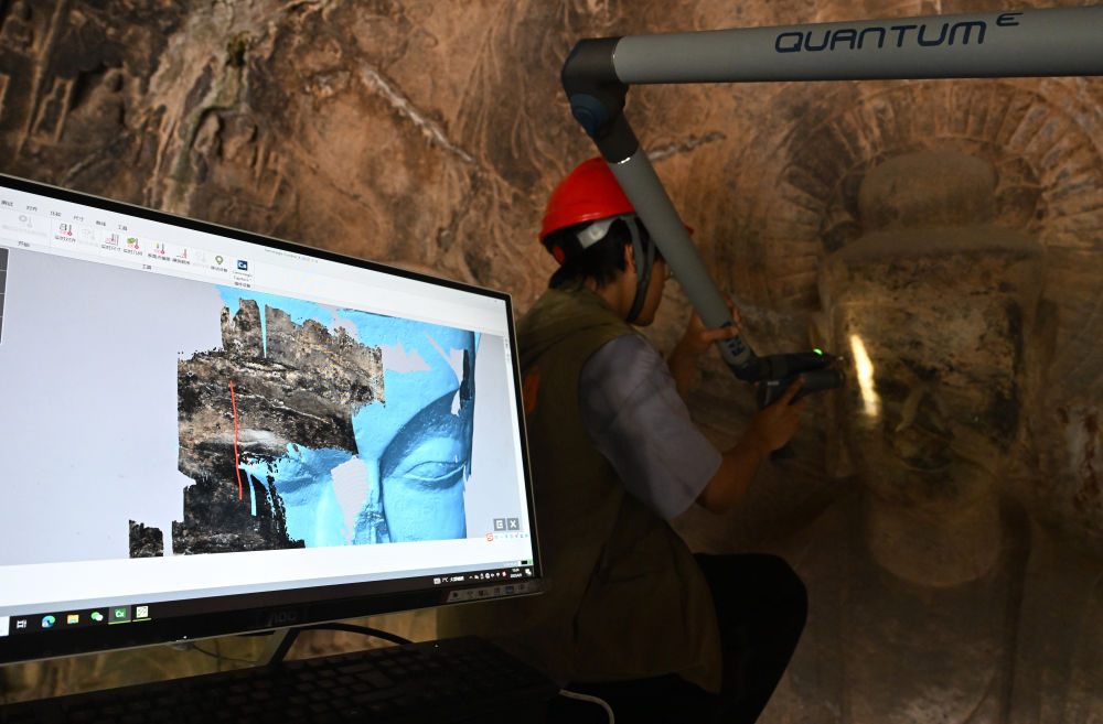 2025年4月9日，武漢大學(xué)文化遺產(chǎn)智能計(jì)算實(shí)驗(yàn)室團(tuán)隊(duì)成員在魏字洞使用關(guān)節(jié)臂掃描儀對(duì)佛像進(jìn)行數(shù)字化掃描。圖片來(lái)源新華社