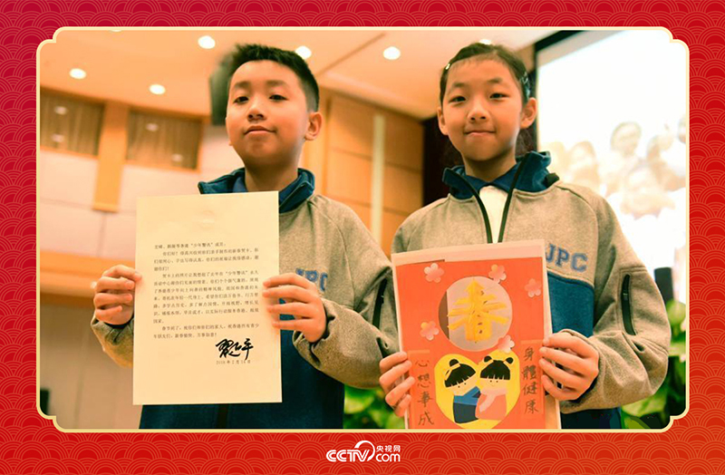 圖為香港“少年警訊”成員郭宏晞（左）展示習(xí)主席回信、羅顥凝（右）展示送給習(xí)主席的賀卡并合影。