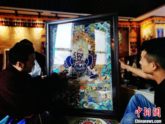 圖為久美尖措(左)與徒弟們展示唐卡作品?！?zhí)砀?攝