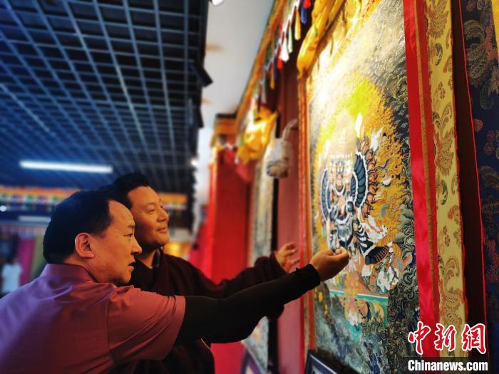圖為久美尖措展示唐卡作品?！?zhí)砀?攝