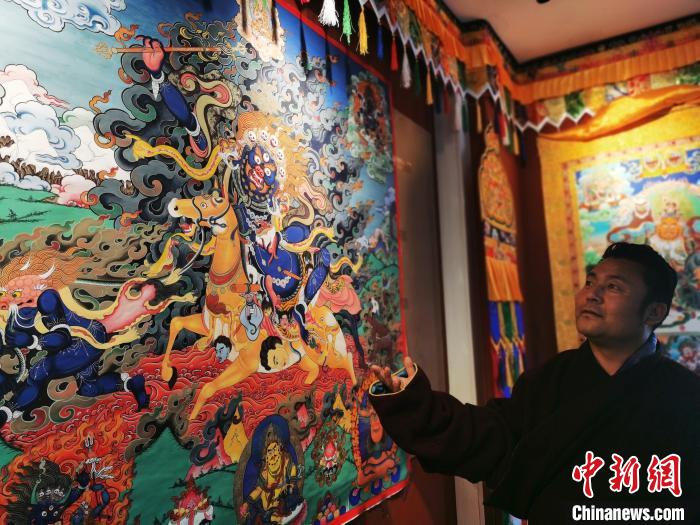 圖為久美尖措展示唐卡作品?！?zhí)砀?攝