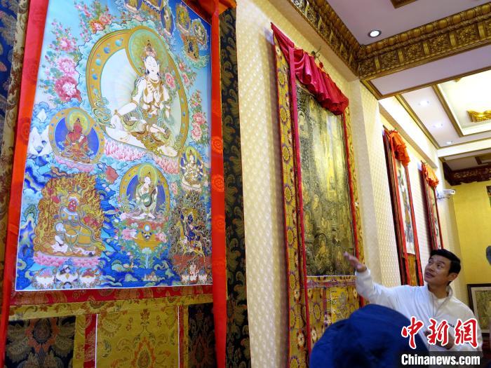 圖為完德尖措展示熱貢龍樹畫苑內(nèi)的唐卡?！?zhí)砀?攝