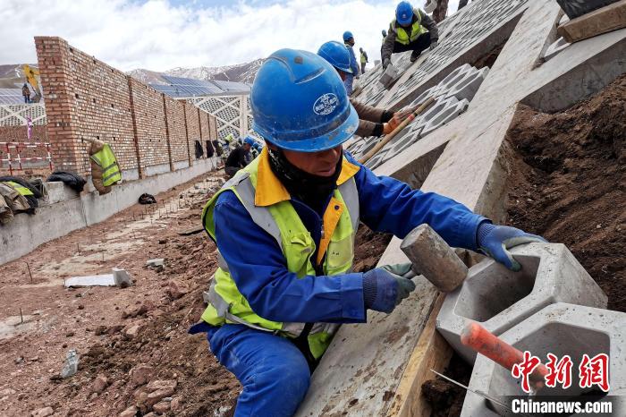 圖為光伏發(fā)電項目施工區(qū)工人在護坡鋪設空心磚?！±铍h 攝