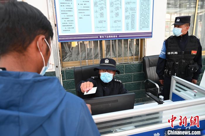 圖為移民管理警察登記完身份信息后將證件歸還給行人?！≮w朗 攝