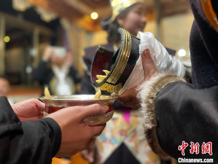 圖為主人在碗中斟滿青稞酒。　冉文娟 攝