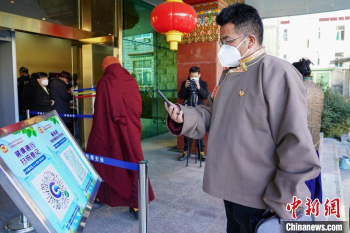 圖為政協(xié)委員掃場所碼進入會場?！〗w波 攝