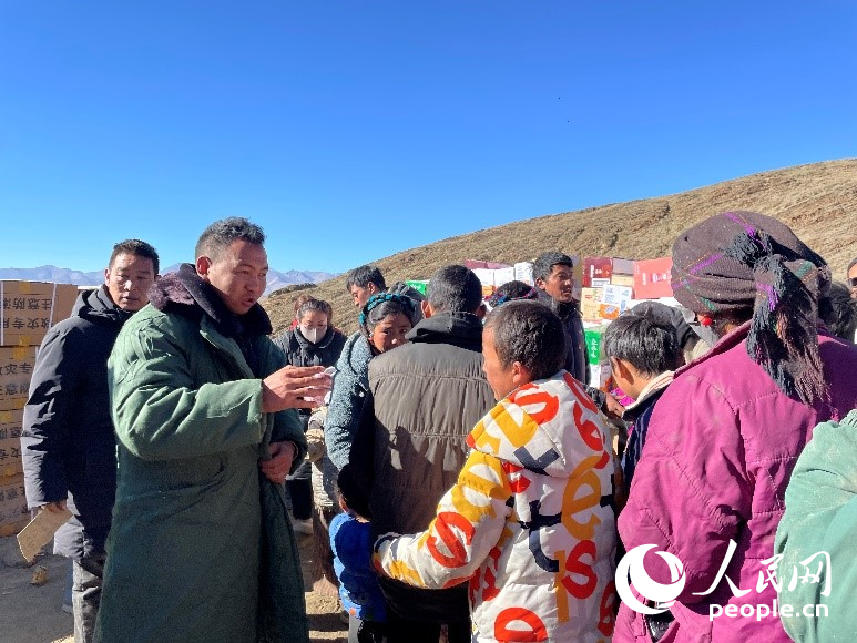 定日縣公安局干警頓珠次仁（左二）正在協(xié)助分發(fā)物資。人民網(wǎng)記者 郝潔攝