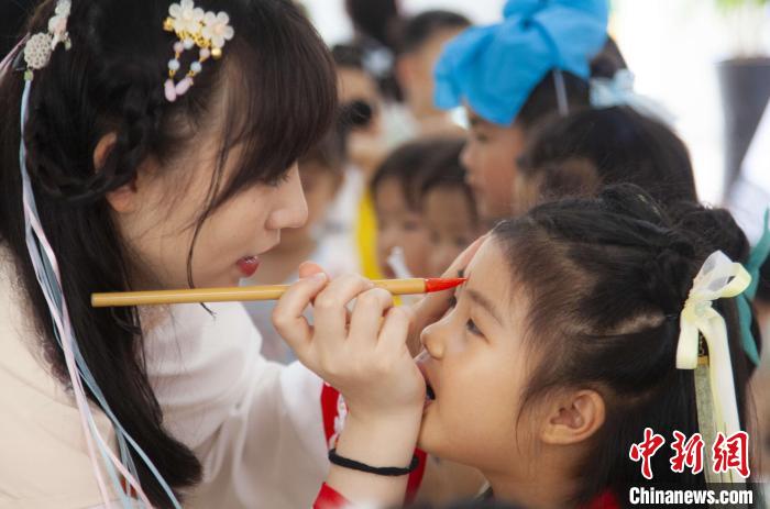 圖為老師在孩子們額頭上點上雄黃，驅(qū)邪辟禍?！《^生 攝